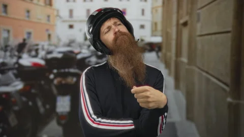 Man wearing helmet strokes beard on narrow cobblestone street flanked by ag.. Stock Footage 313857773