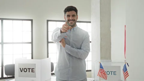 Man wearing an 'i voted' sticker giving thumbs up beside a ballot box with .. Stock Footage 337373476