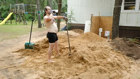 Man wearing just briefs drinking beer while taking break form shoveling sand Video stock 245889332
