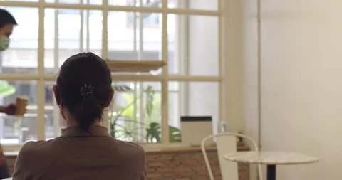Man wearing mask and talking with friend in shop sit far from other Stock Footage 133905798