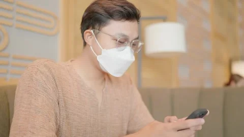 Man wearing a mask and using a cell phone at a beverage shop Stock Footage 251974268