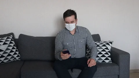 Man wearing mask using smartphone working from home office Stock Footage 126710680