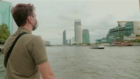 Man wearing mask while exploring urban riverfront landscape. Stock Footage 257223429