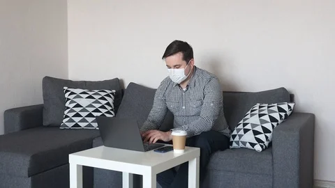 Man wearing mask working on from home his laptop Stock Footage