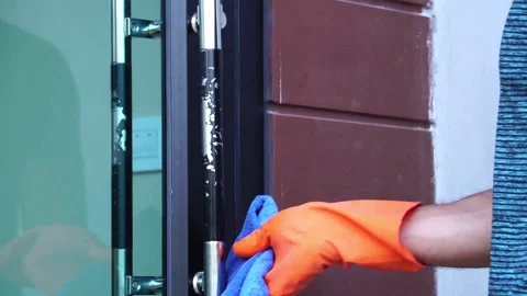 Man wearing plastic glove using aerosol spray alcohol for cleaning store door Stock Footage 147868600