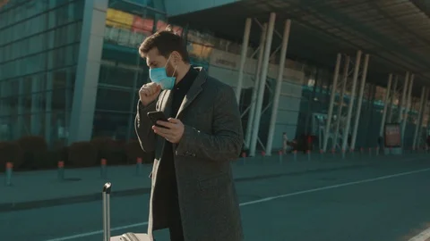 Man wearing Protective Face Mask use phone coughs hold suitcase COVID-19 Stock Footage 126619200