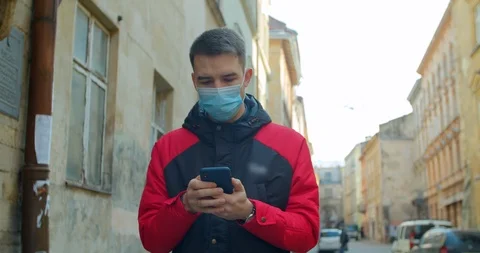 Man wearing Protective Face Mask use phone. COVID-19 coronavirus infection Stock Footage 126760262