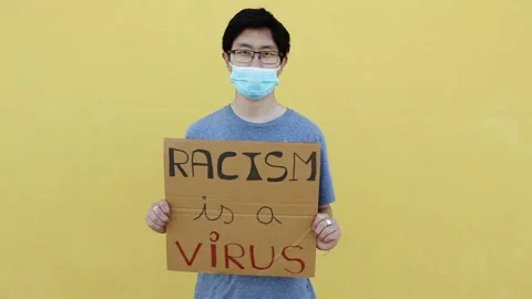 Man wearing protective face mask holding a poster against asian racism Stock Footage 152158066