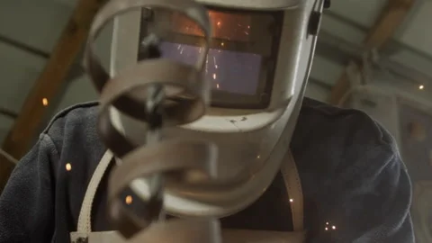 Man wearing a protective face shield against flying sparks while soldering Stock Footage 274948194