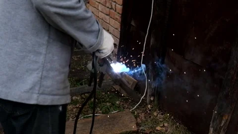 A man wearing a protective mask performs welding work outdoors Stock Footage 297935014