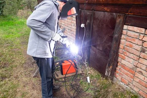A man wearing a protective mask performs welding work outdoors Stock Photos