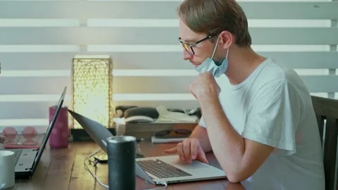 Man wearing a protective mask sitting at table in cafe with laptop Stock Footage 138031357