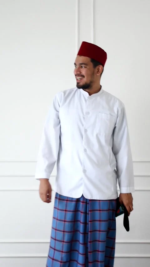 A man wearing a red cap, white shirt and purple fabric in a white painted room Video stock 267385977