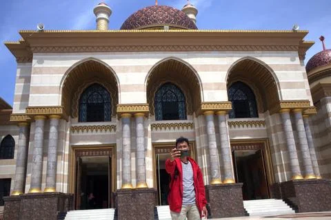 A man wearing a red jacket and carrying a bag took a photo in front of a be.. Stock Photos
