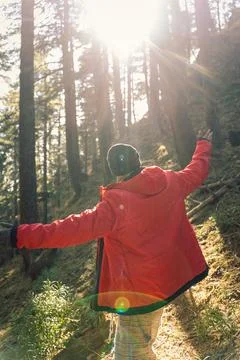 A man wearing a red jacket stands with arms wide open, enjoying the warm sunl Stock Photos