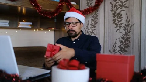 Man wearing Santa Claus hat opening Christmas present and looking disgusted Stock Footage 143867930