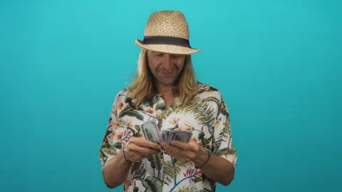 Man wearing straw hat and floral shirt counting a thick stack of crisp us d.. Video stock 314642825