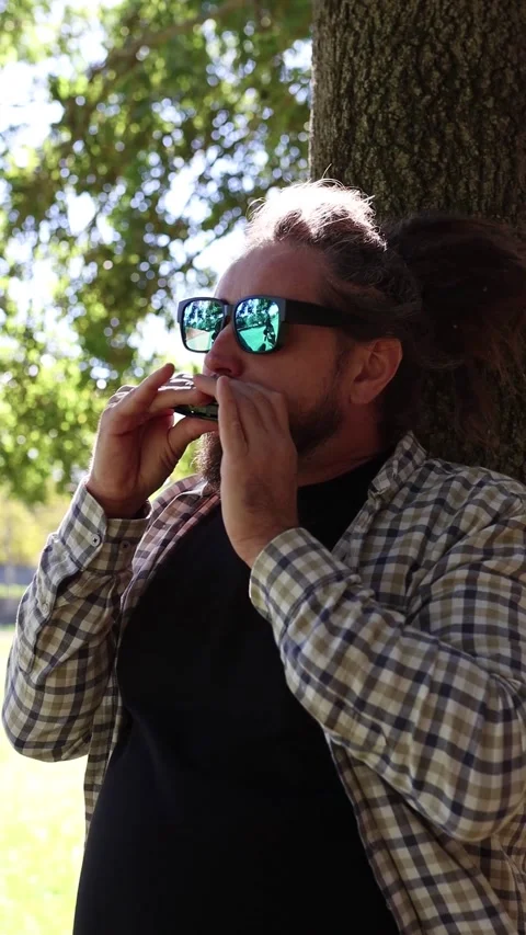 Man Wearing Sunglasses Playing Harmonica, Mouth Organ. Vertical Video Stock Footage 291478492