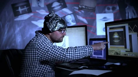 Man wearing a Tinfoil Hat looking at UFO evidence Stock Footage 160695686