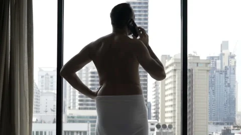 Man wearing towel and speaking on cellphone in his apartment Stock Footage 93222353