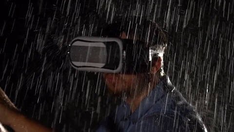 Man wearing virtual reality glasses and playing game outside in the rain. VR Stock Footage 80388115
