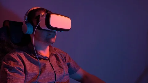 A man wearing virtual reality glasses and headphones is listening to music while Stock Footage 115089424