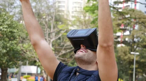 Man wearing virtual reality goggles outside in a park. Stock Footage 67634484