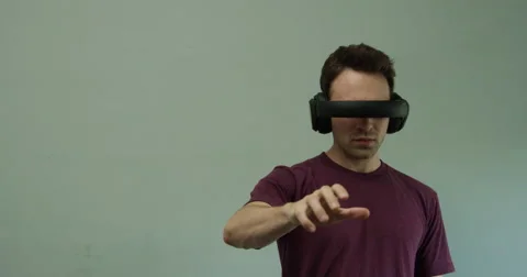 Man wearing virtual reality headset operates imaginary controls Stock Footage 64298173