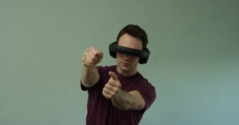 Man wearing virtual reality headset plays car driving game, straight-on Stock Footage 64305328