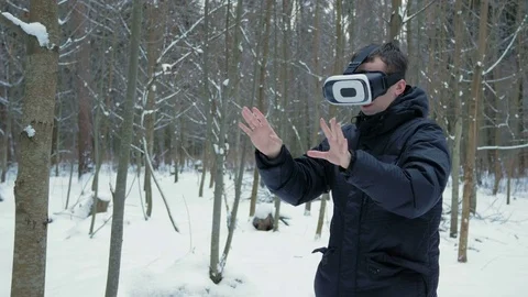 A man wearing a virtual reality headset in the winter in a snowy forest. He Stock Footage 71208697