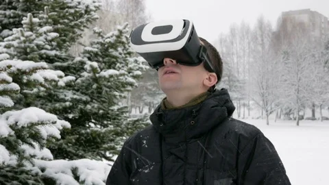 A man wearing a virtual reality headset in the winter in a snowy forest. Big Stock Footage 71215445