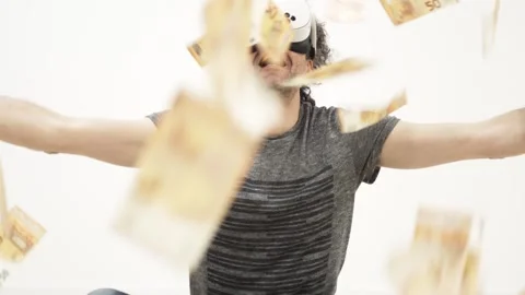 Man wearing virtual reality headset catches falling money 스톡 동영상 309772979