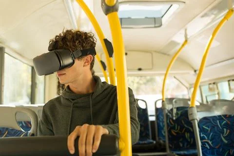 Man wearing virtual reality headset gripping seat back and standing inside bus Stock Photos