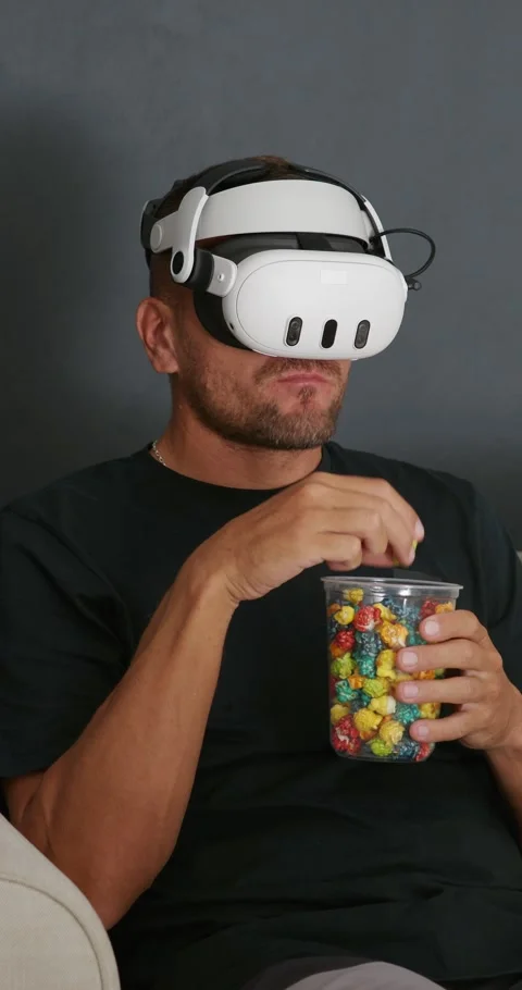Man wearing VR goggles sitting on sofa eating popcorn watching 3d movie. Stock Footage 257992269