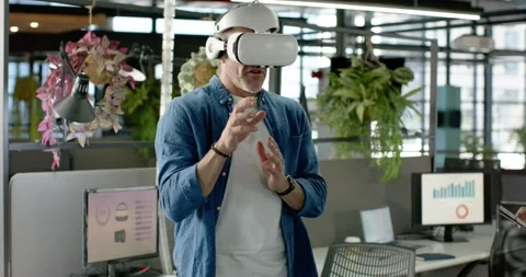 Man wearing VR headset calibrating controller while colleagues reviewing tablet Stock Footage 317718779