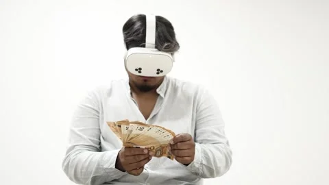 Man wearing VR headset counting Indian Rupees banknotes on white background 스톡 동영상 309772729
