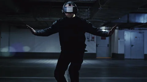 Man wearing vr headset dancing in an underground parking garage Stockbeeldmateriaal 332539616