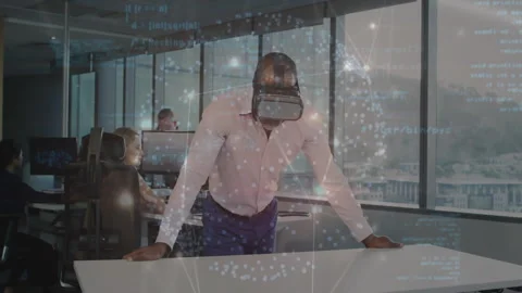 Man wearing VR headset at desk with coworkers typing among floating code Stock Footage 309104079
