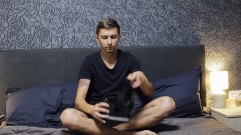Man wearing VR Headset sit on the bed. Looking around. Watch VR video Stock Footage 98038844