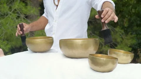 A man wearing in white doing healing sound massage with tibetan singing bowl Stock Footage 213891650