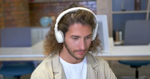 Man wearing white-headset hearing audio, leaning forward, nodding and reading Stock Footage 342031010