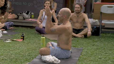 Man wearing a wireless microphone leading a yoga or inspirational talk clapping Stock Footage 110733077