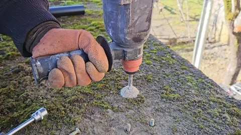 A man wearing work gloves makes holes using a hammer drill. Stock Footage 296755178