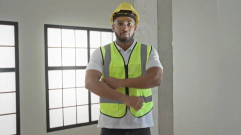 Man wearing yellow hardhat and reflective vest with arms crossed in a build.. Video stock 337439489