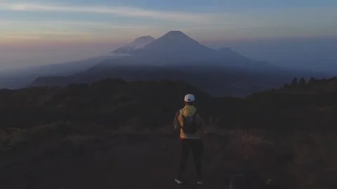 Man wearing yellow jacket looking at mountain in front of him Stock Footage 291490087