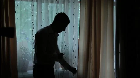 The man wears the clothes against the window. The silhouette of a man. Stock Footage 65331730
