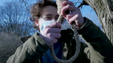 Man wears face mask, thinks of hanging himself. Trying to commit suicide in park Stock Footage 149306786