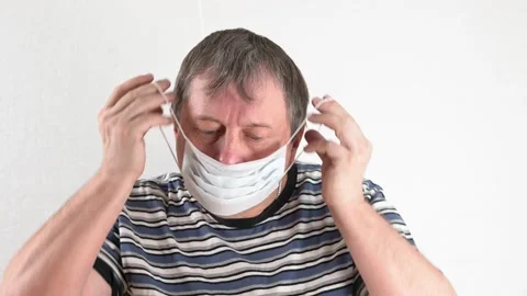 The man wears a mask, crumples image covid 19, throws it and takes off his mask Stock Footage 138169265