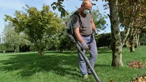 Man Wears a Mask to Using Blower at Garden During The Covid-19 Pandemic Stock Footage 140675427