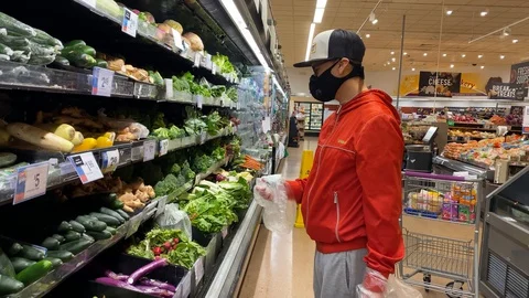 A man wears a mask while holding ginger at a Giant grocery store Stock Footage 129507275